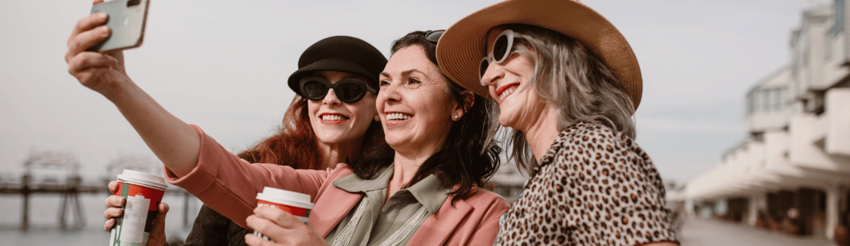 Drei Frauen in der Lebensmitte lachen gemeinsam – Verbundenheit und Lebensfreude